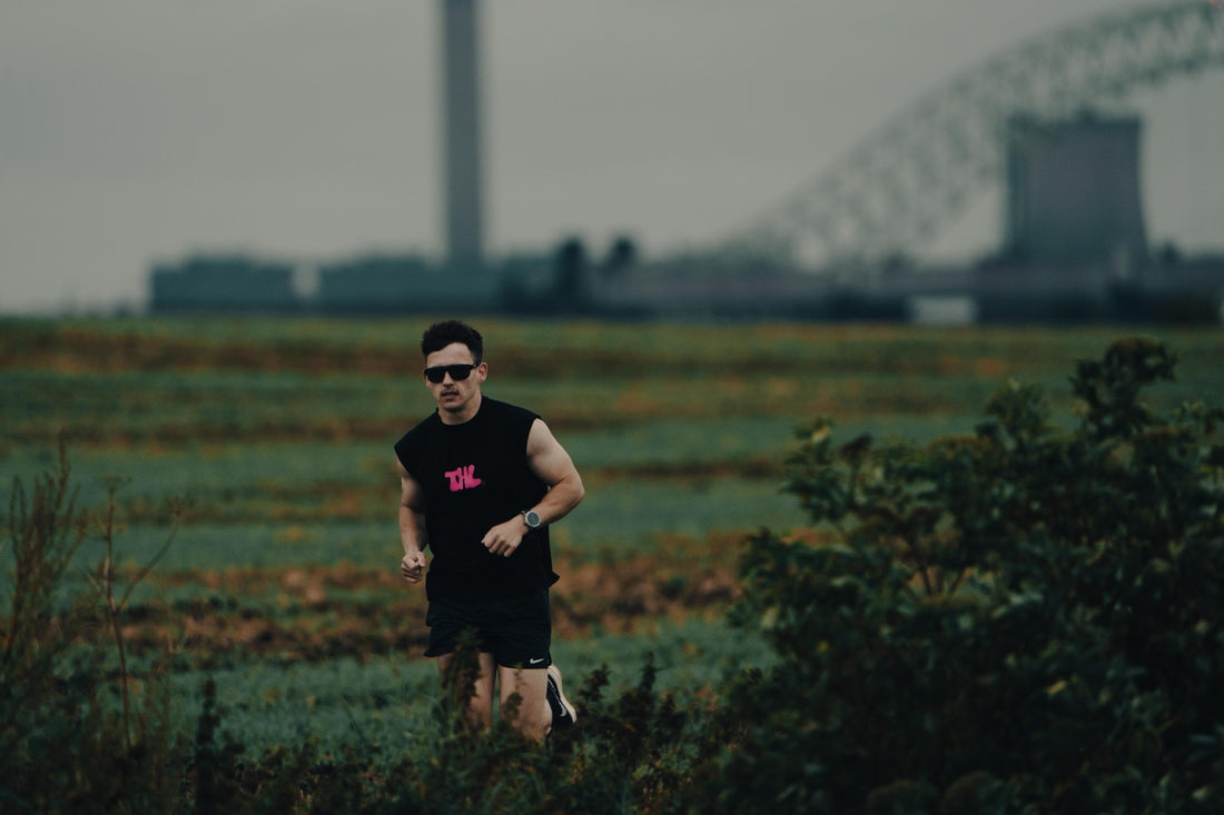 Man running through grass fields with glasses on.