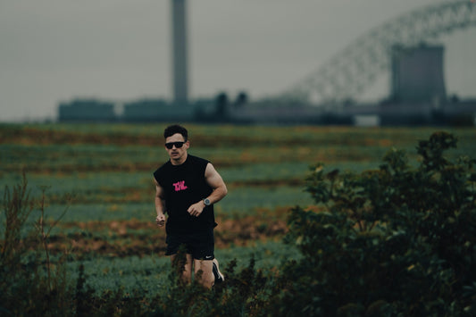 Man running through grass fields with glasses on.