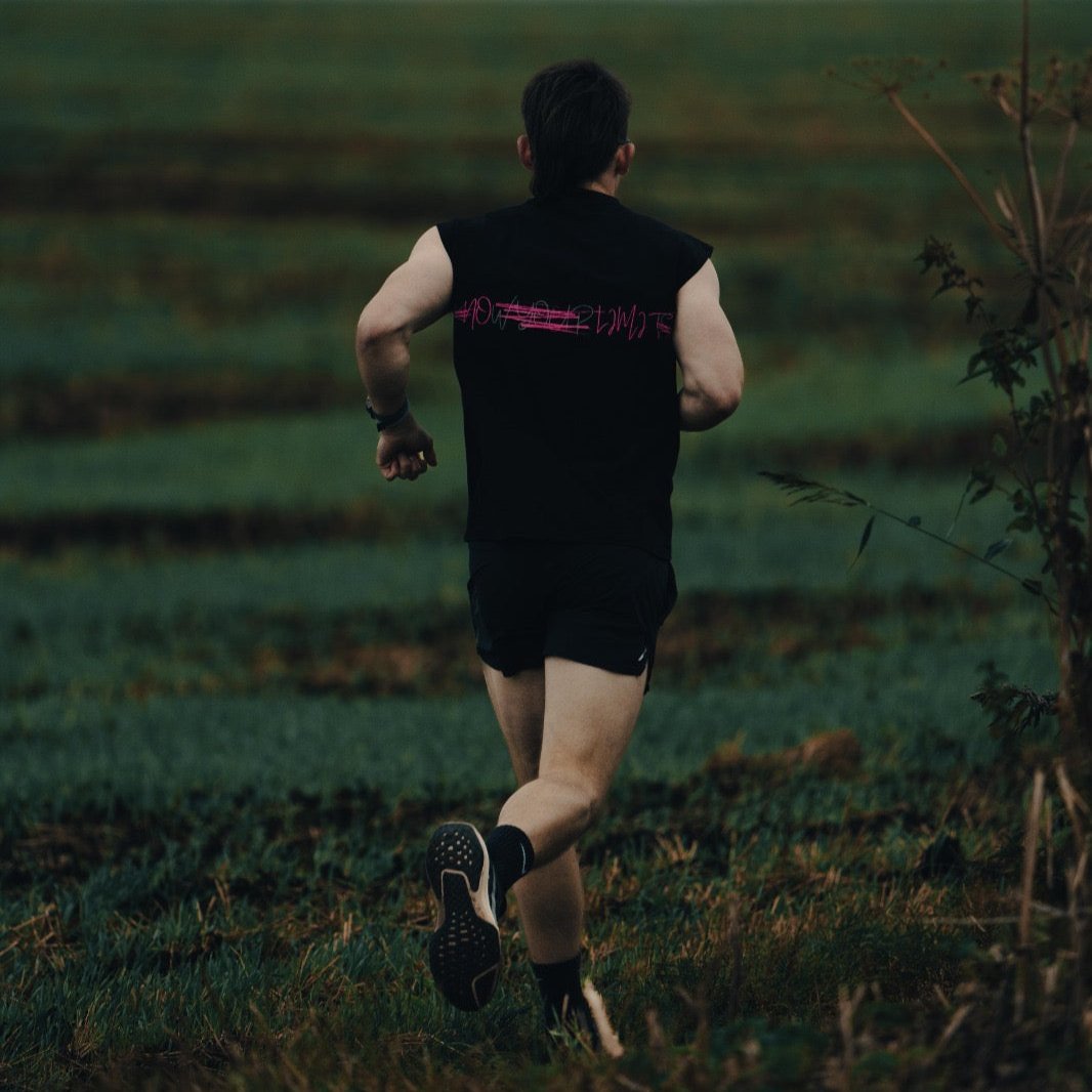 Man running through a field wearing a THL Hybrid Tank