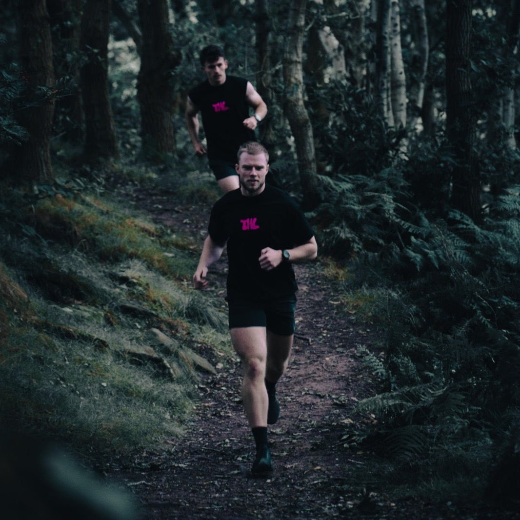 2 Men running though a forest wearing The Hybrid Life T Shirt and Tank Top